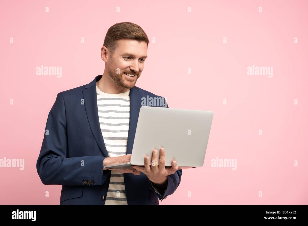 Smiling relaxed middle-aged man in office look holding laptop computer isolated on pink background Stock Photo