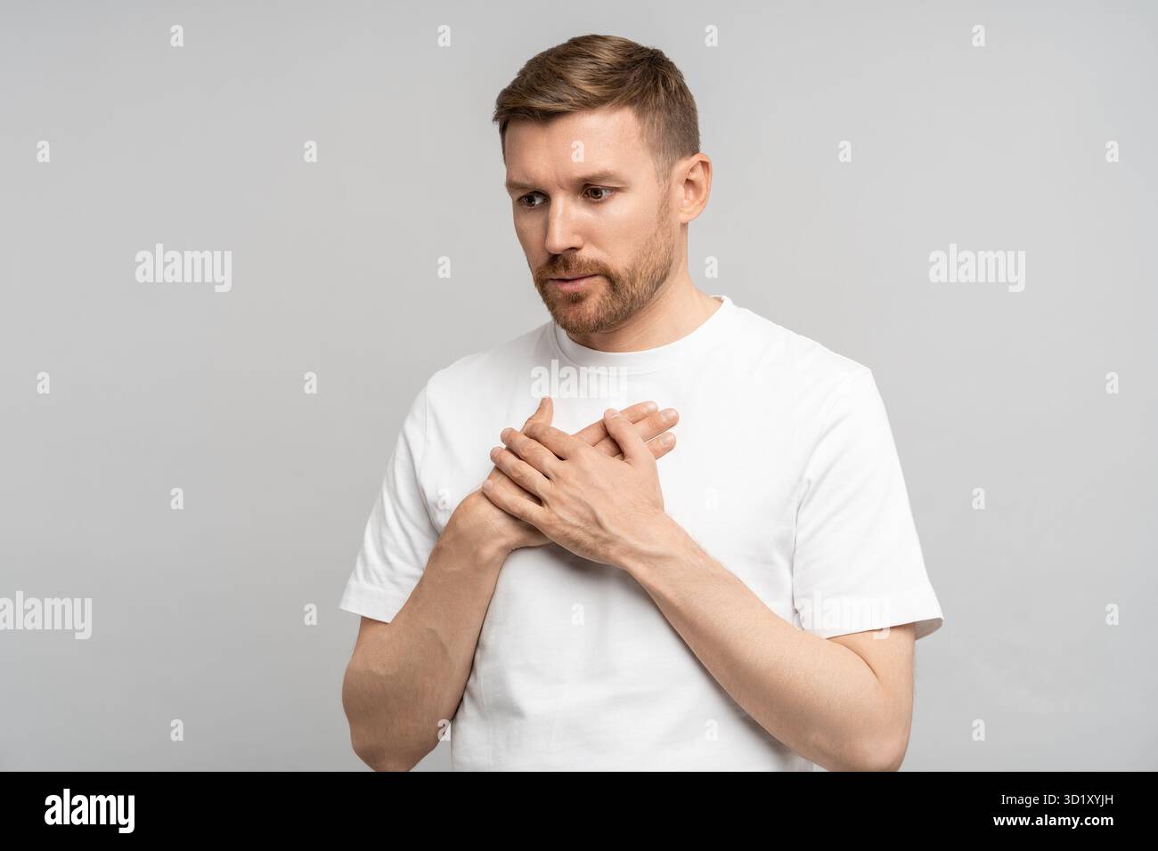 Man has breathing problems, panic attack, suffocation holding hands on chest on gray background. Stock Photo