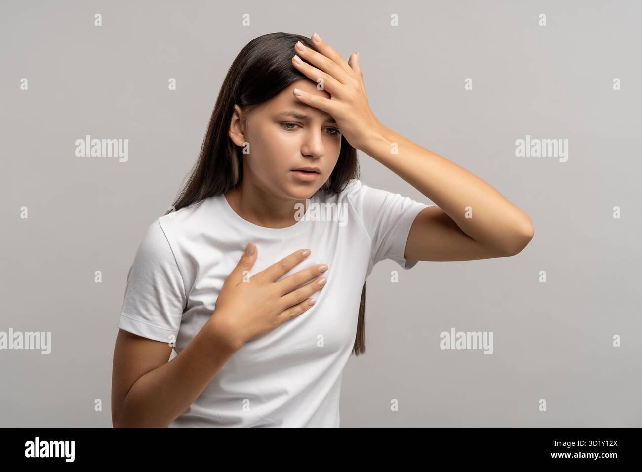 Teen girl feeling headache nausea touching chest forehead on gray background. Stock Photo