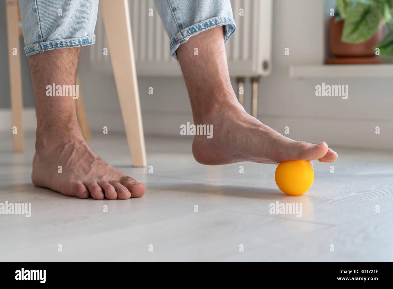 Man using silicone ball for foot massage during long sedentary work, legs close-up. Stock Photo