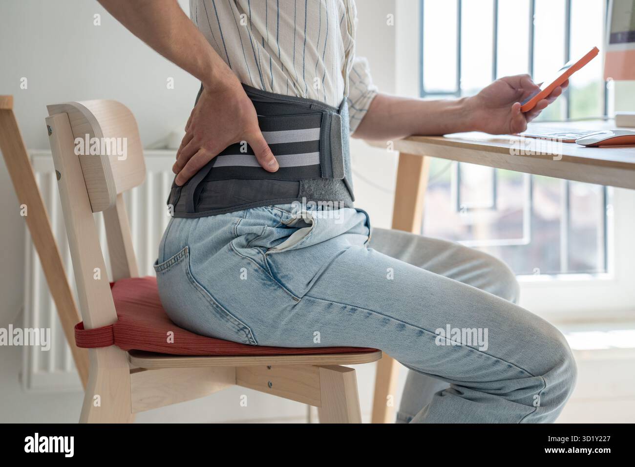 Man freelancer wearing back support belt working remotely from home Stock Photo