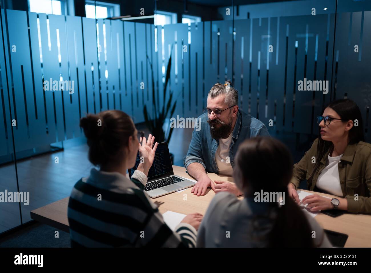 A diverse team of young professionals collaborates in a modern office conference room. Businesspeople discuss strategy, technolo Stock Photo