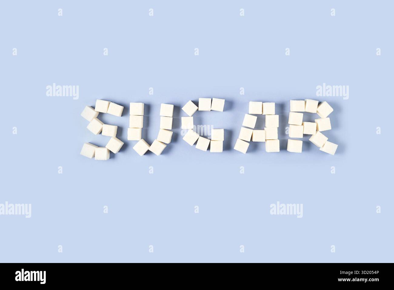 Arrangement of white sugar cubes forming the word sugar on light blue Stock Photo