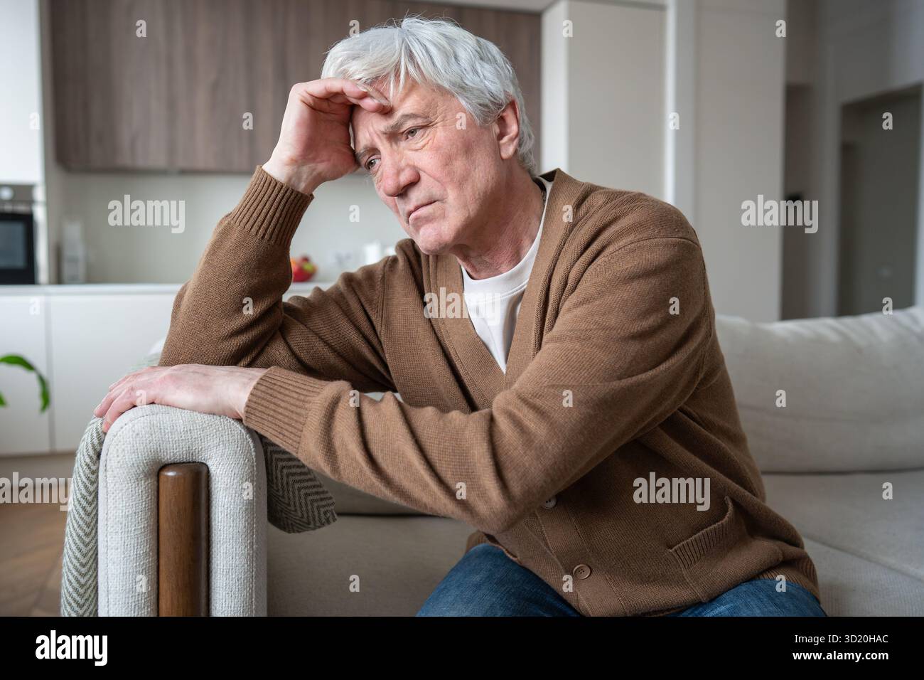 Lost sad elderly man with Alzheimer dementia sitting slumped on sofa, silent despair frustration Stock Photo