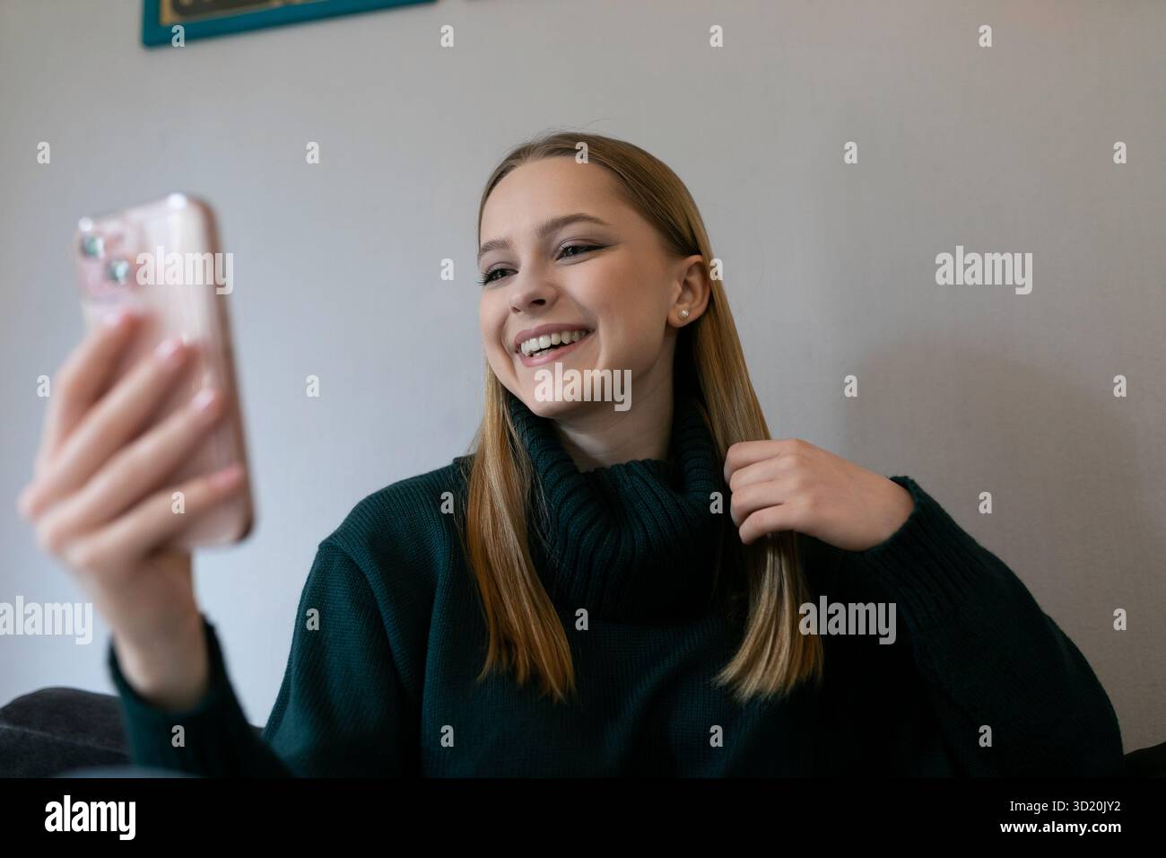 Young woman enjoying a virtual conversation while sitting on a couch in a cozy living room setting Stock Photo