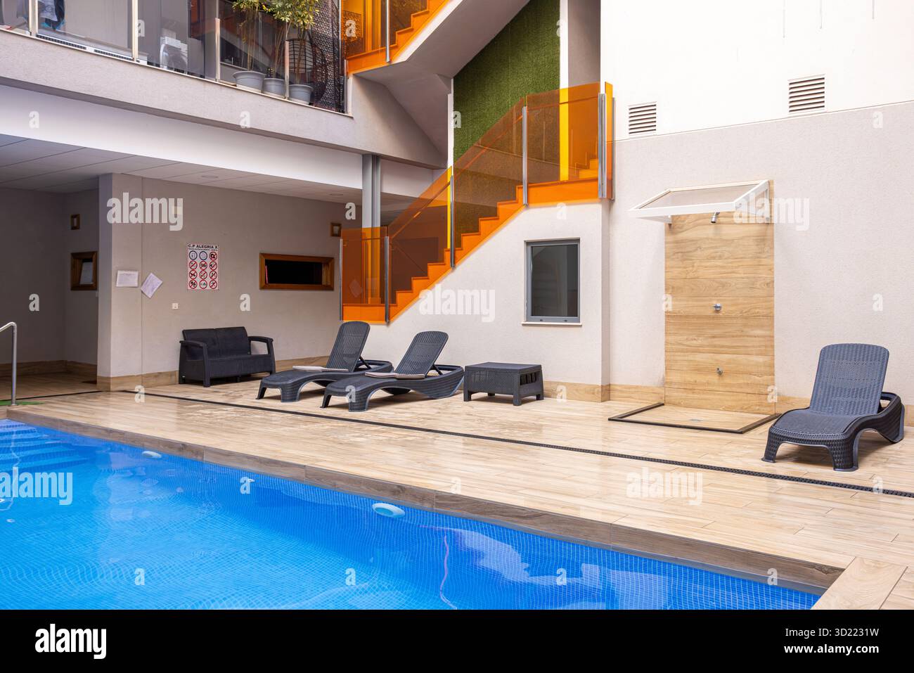 Modern pool area in apartment building with loungers, shower, and ...