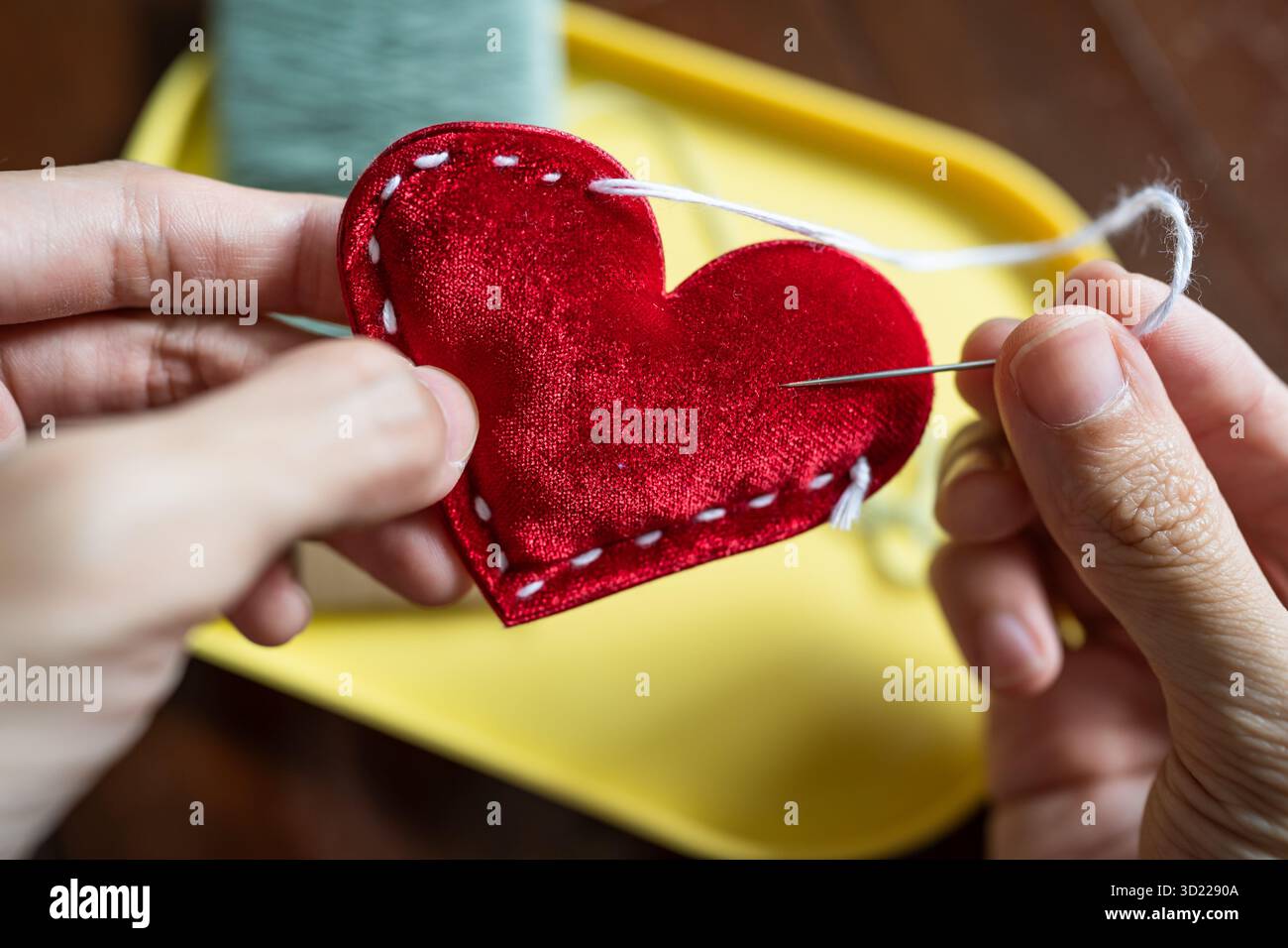 Stitching a red heart shape Stock Photo