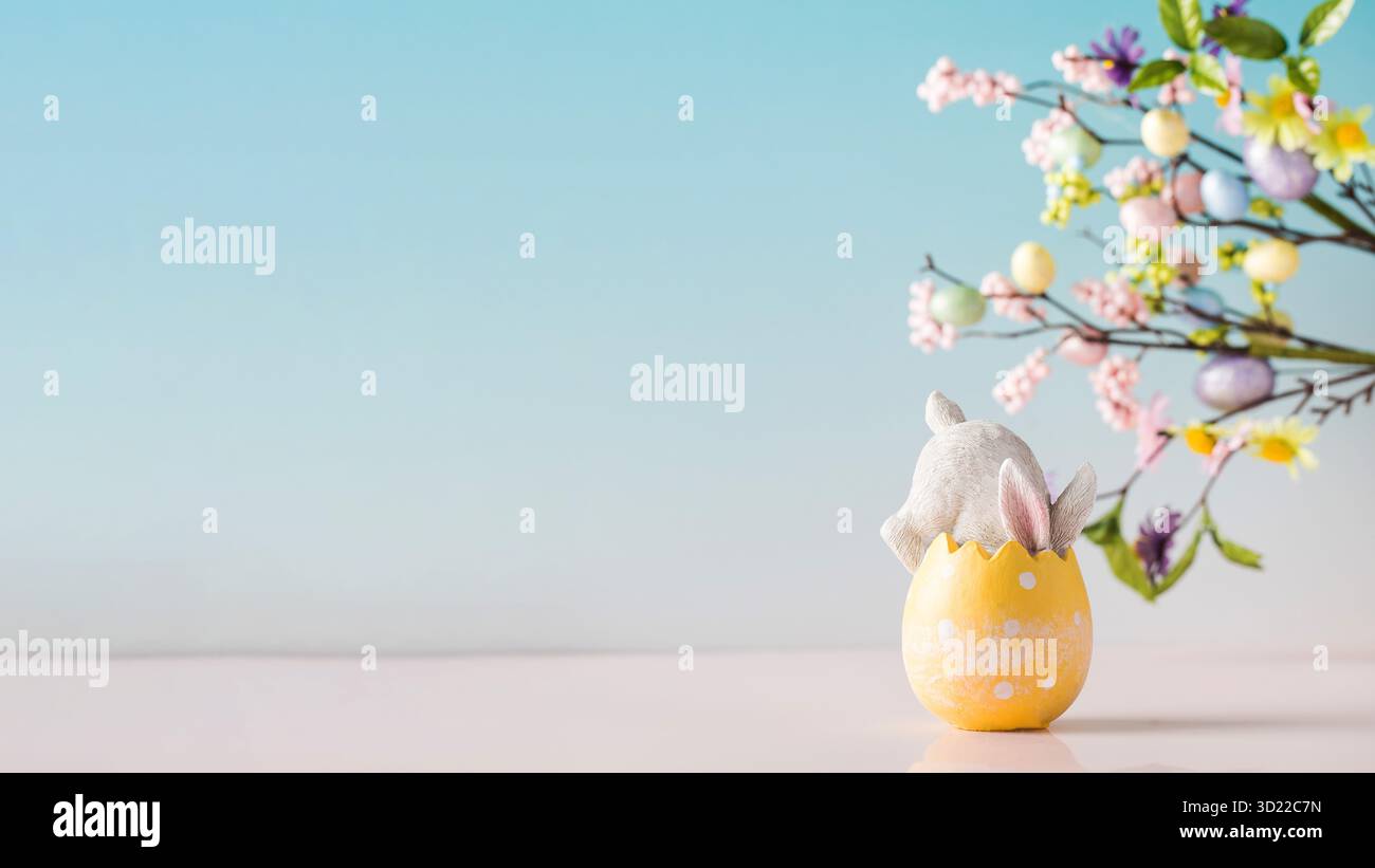 A white rabbit hid in an Easter egg on a blue background. Festive Easter card. Copy space. Stock Photo