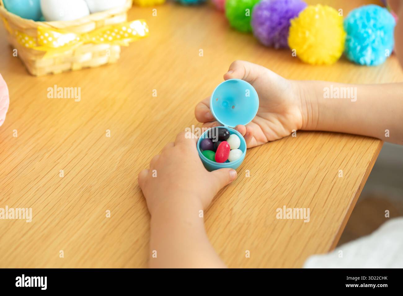 Child opening easter egg with colorful candy surrounded by festive decorations for spring celebration. Easter. Stock Photo