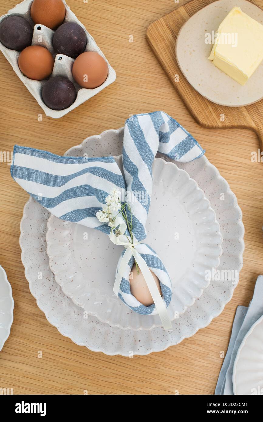 Easter egg wrapped in linen napkin in the shape of bunny with ears. Happy Easter Stock Photo