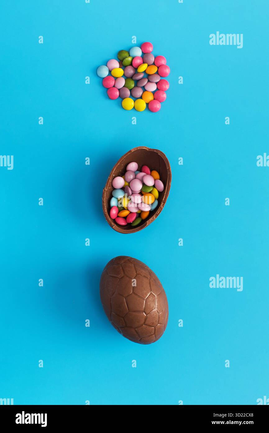 Chocolate Easter egg with colorful dragees inside on a blue. Happy Easter. Stock Photo