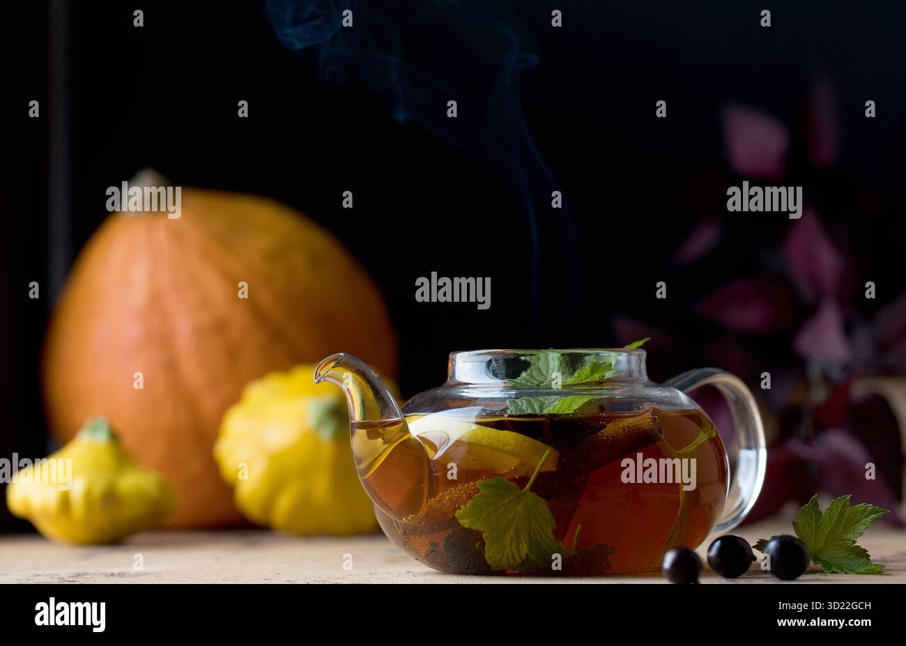 Autumn tea with lemon, spices and currant berries in a teapot on the background of pumpkins and squash. Autumn mood. Stock Photo