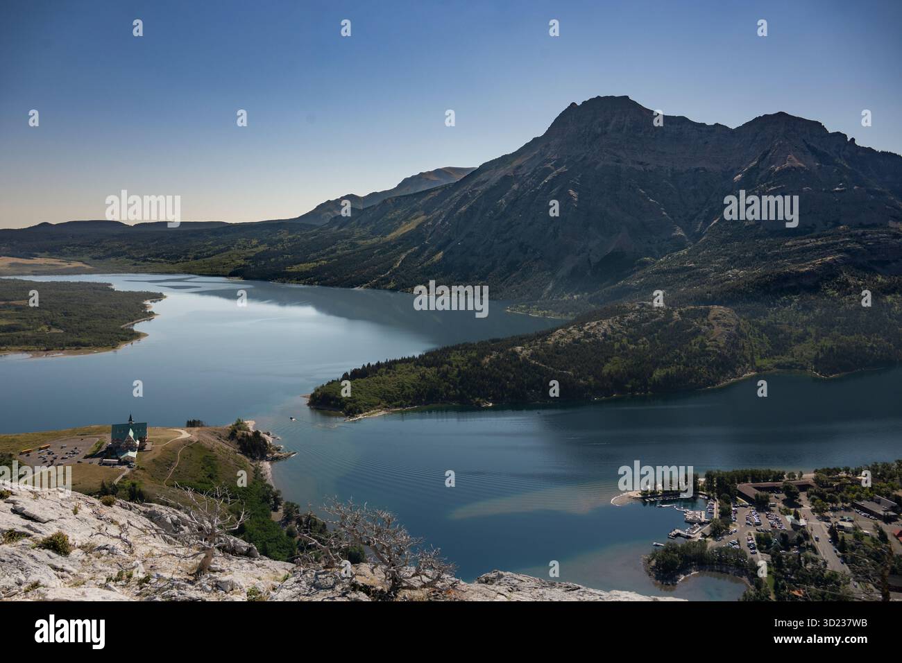 A serene lake surrounded by mountains under a clear blue sky with a ...