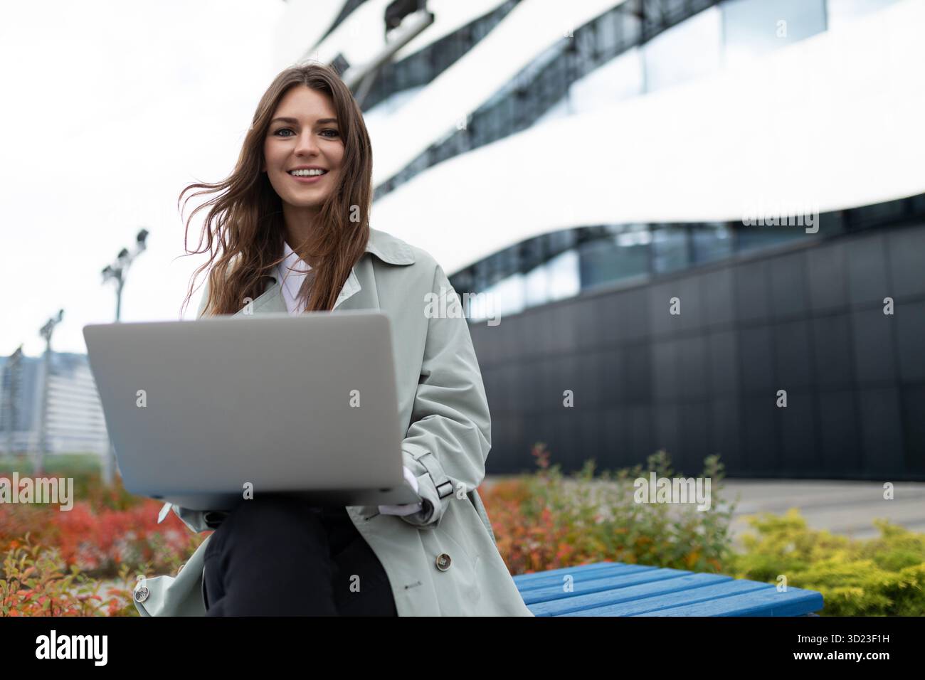 Young woman working on laptop next to office outside Stock Photo