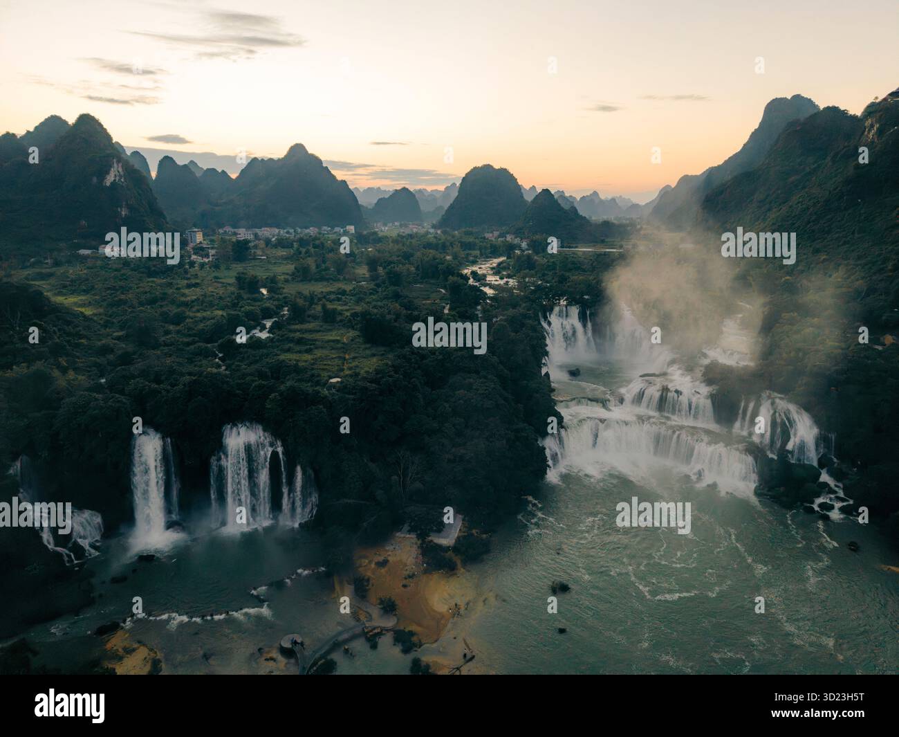 Aerial view of cascading waterfalls amid lush greenery and distant ...
