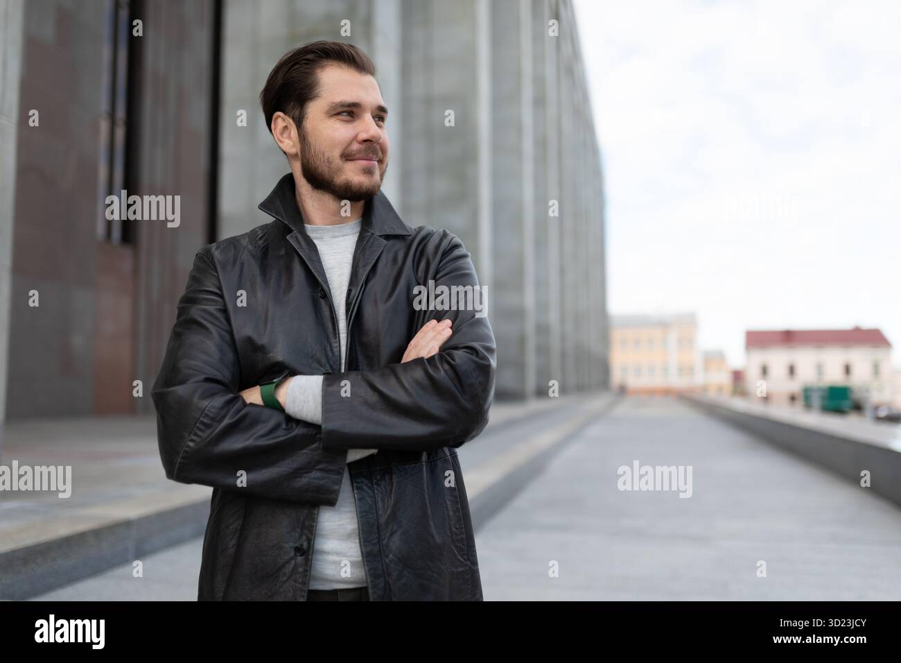 Pretty young caucasian man with hands on his chest stands against the background of a gray building Stock Photo