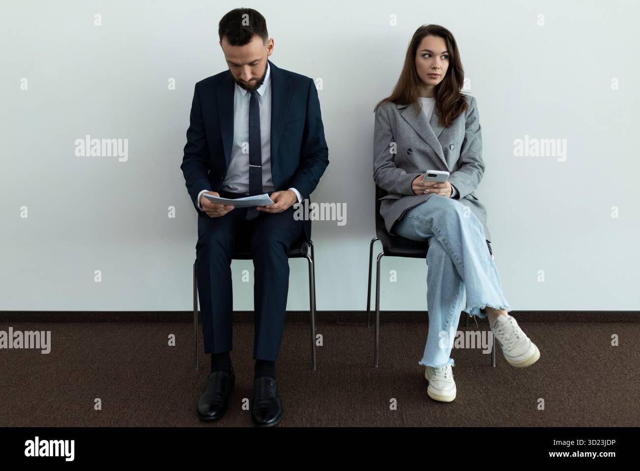 Two young professionals in business suits waiting in line for an interview Stock Photo