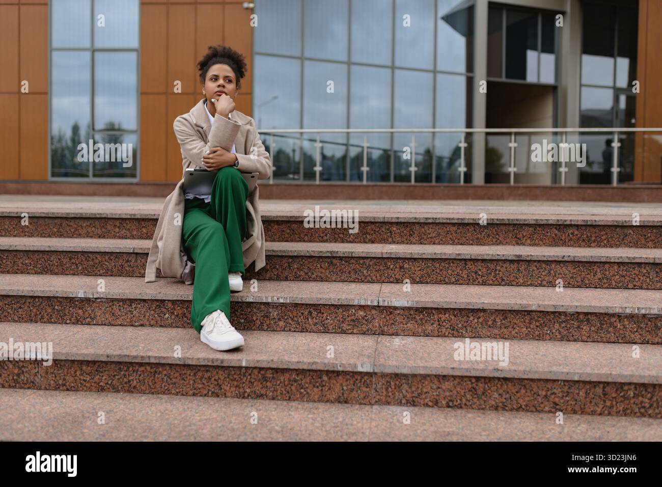 Serious african american woman lawyer sitting on steps of city building Stock Photo
