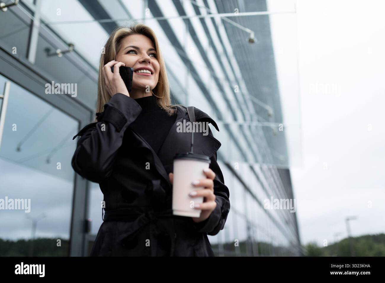 Half-length portrait of a middle-aged blonde businesswoman with a mobile phone and a cup of coffee, concept of successful busine Stock Photo
