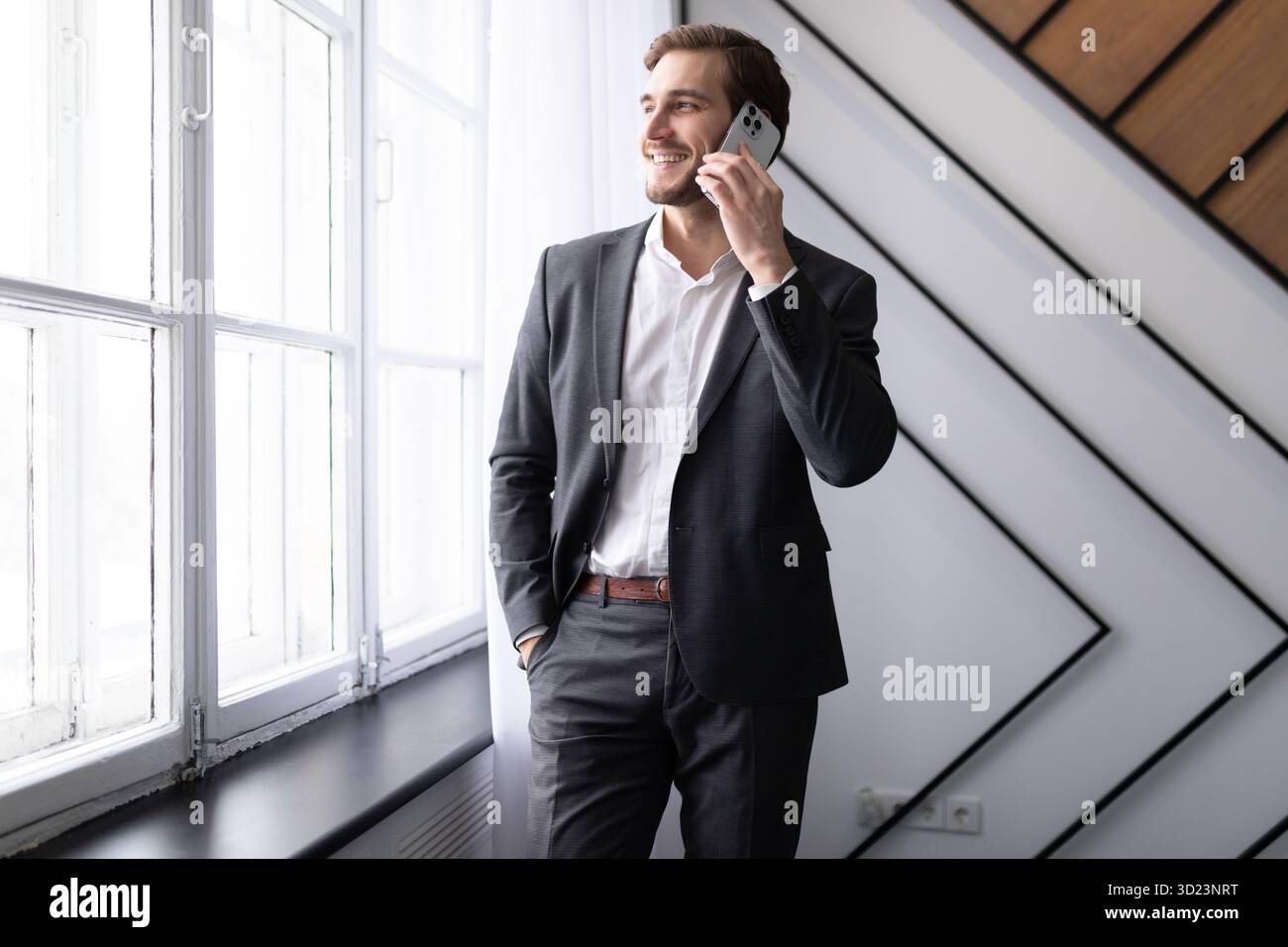 Young businessman talking on a mobile phone looking out the window in the office Stock Photo