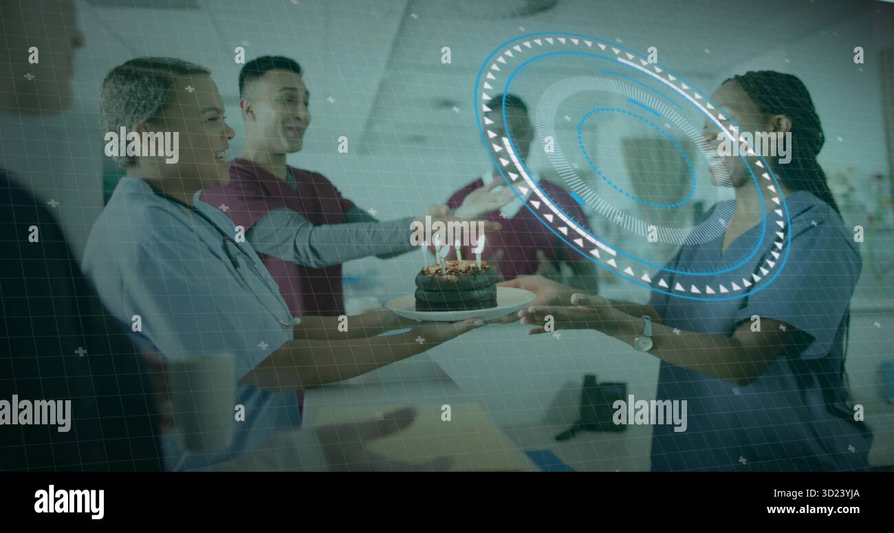 Scrub-clad team passing chocolate cake with lit candles on plate in hospital corridor, celebrating Stock Photo