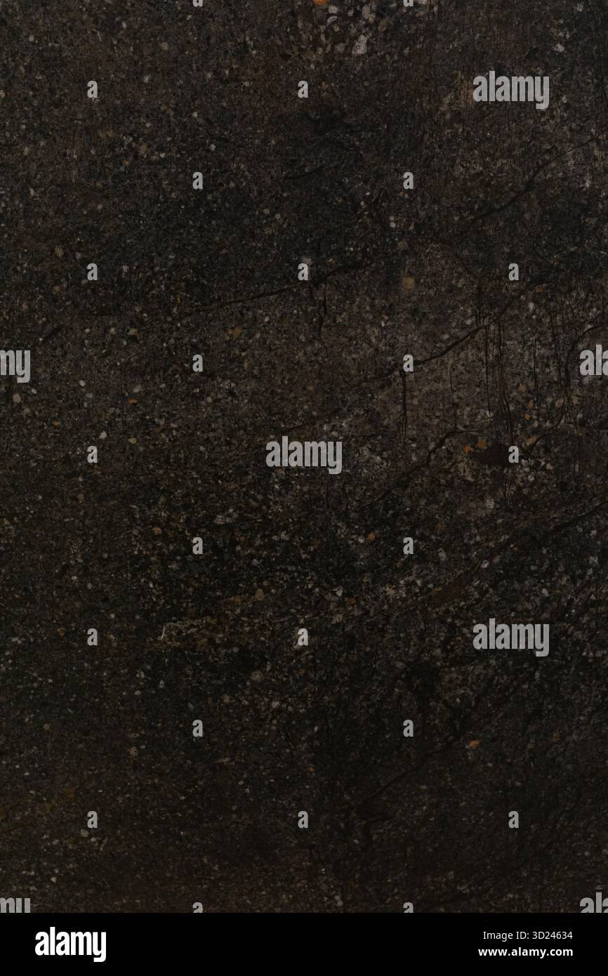 Dark textured surface displays natural patterns and variations under subtle light in a close-up view Stock Photo