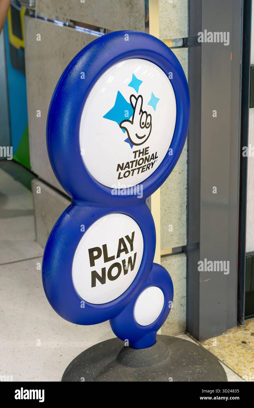 Close view of a floor standing play now, the National Lottery sign outside a UK shop entrance. Stock Photo