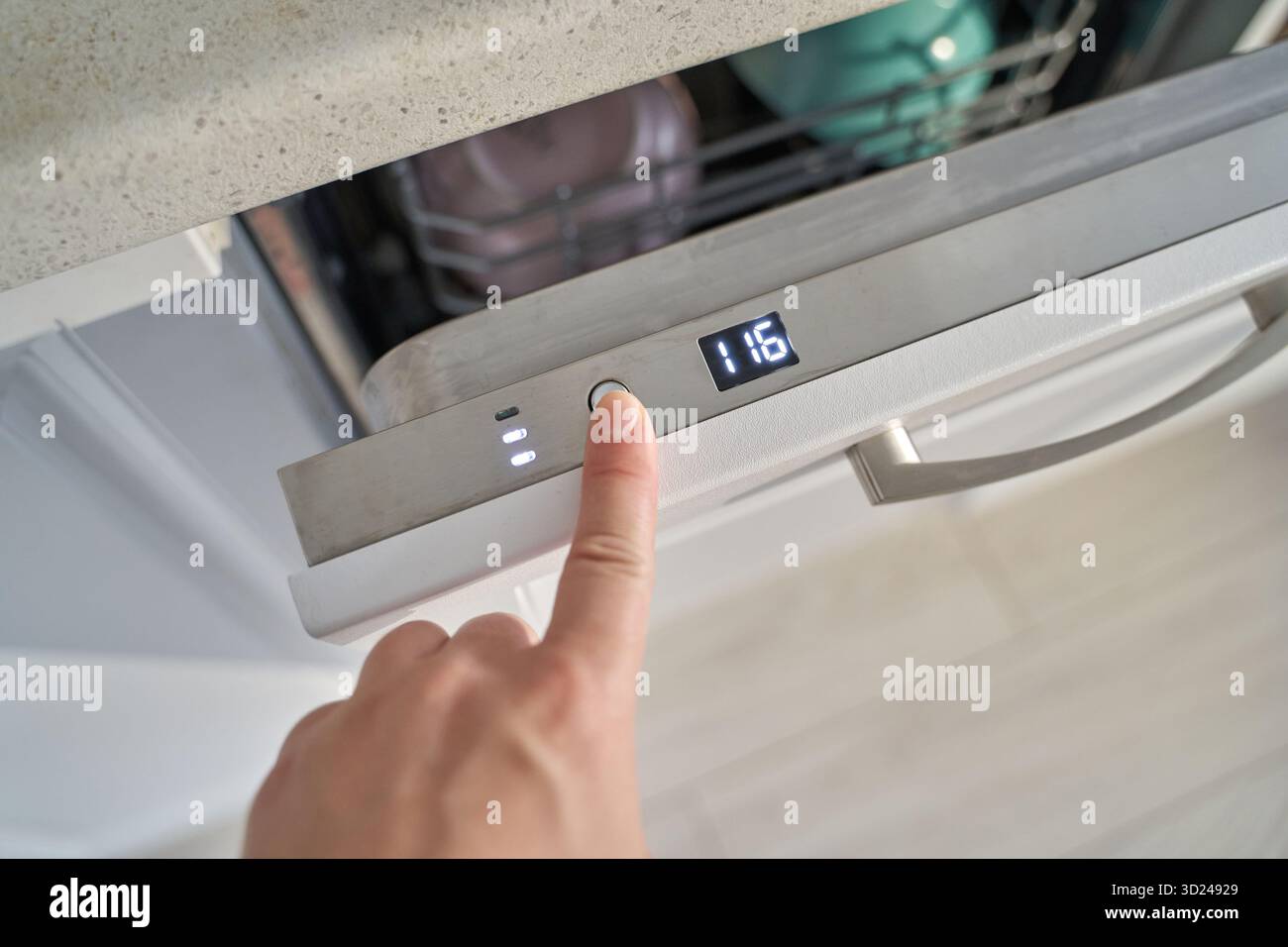 Female hand pressing button on modern dishwasher control panel in kitchen Stock Photo