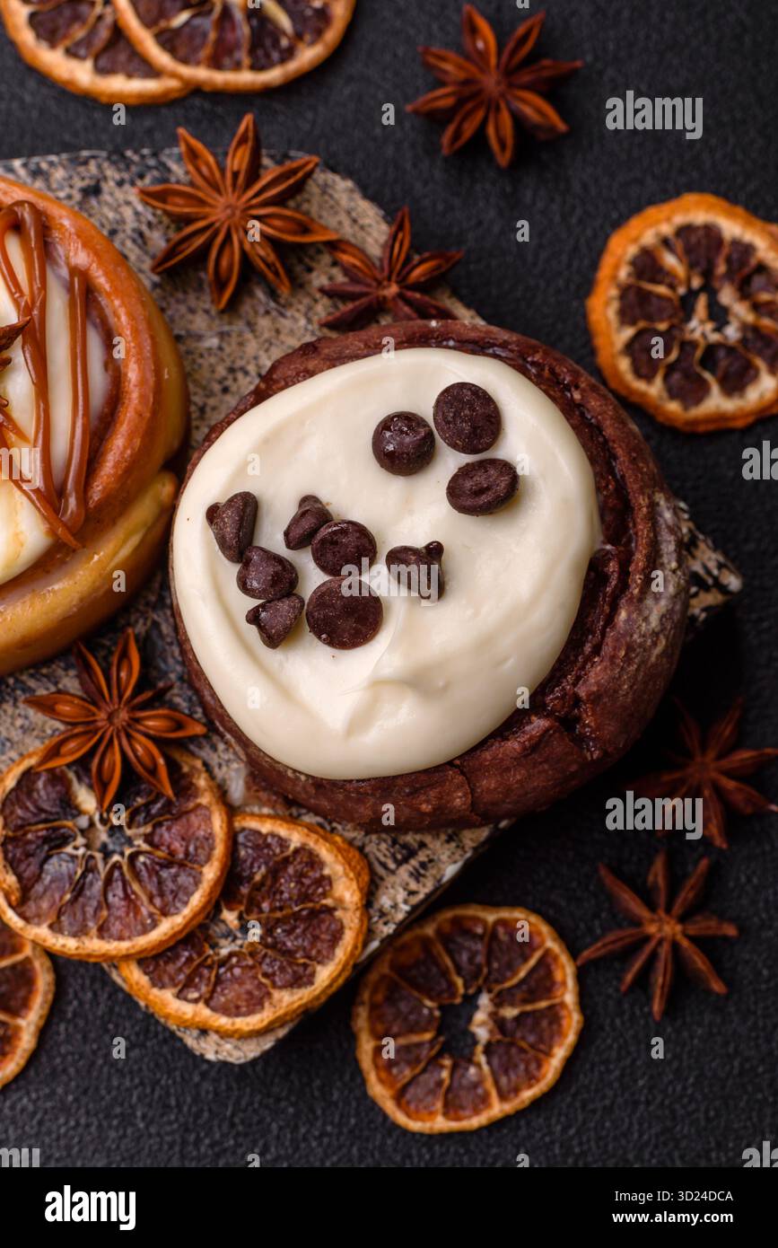 Cinnamon roll, a sweet bun with citrus, cherries, and chocolate, a Danish dessert with cream Stock Photo