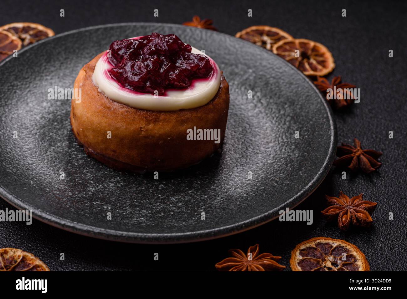 Cinnamon roll, a sweet bun with citrus, cherries, and chocolate, a Danish dessert with cream Stock Photo