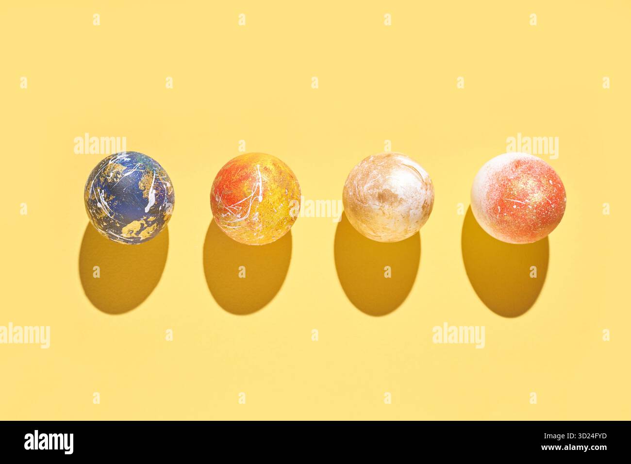 Colorful marbled balls on yellow background with shadows casting patterns Stock Photo