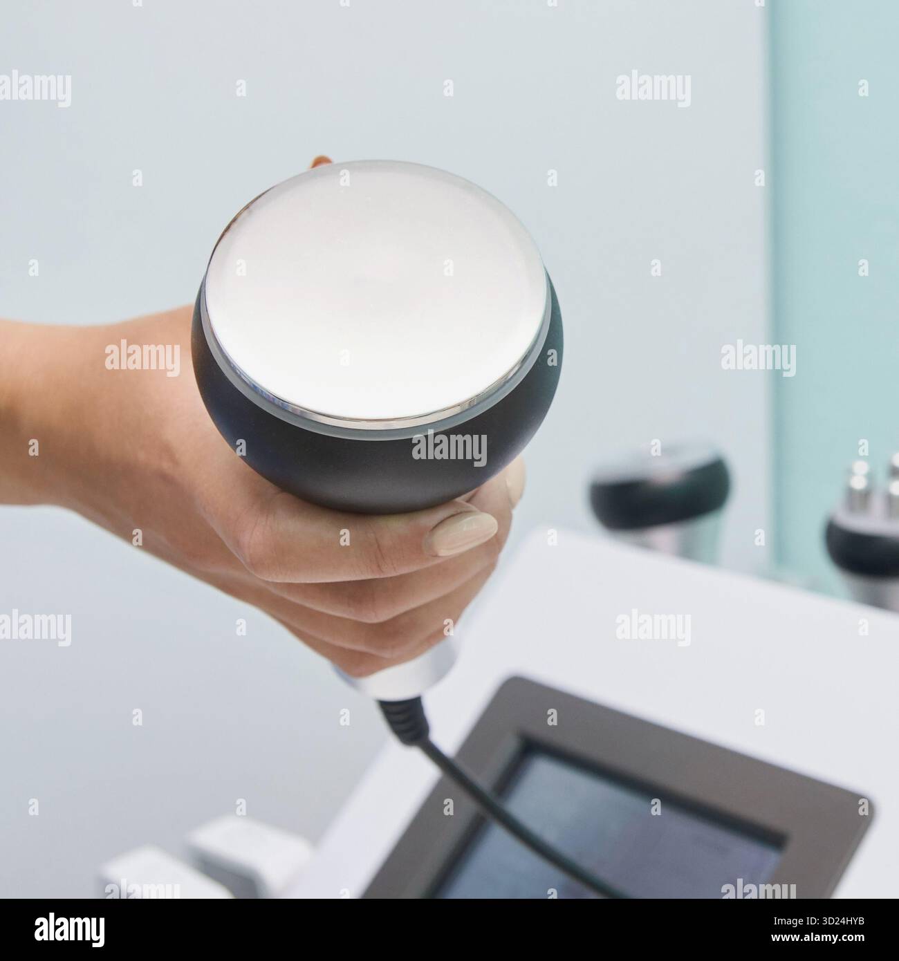 Hand holding ultrasonic cavitation device for non-invasive body contouring Stock Photo