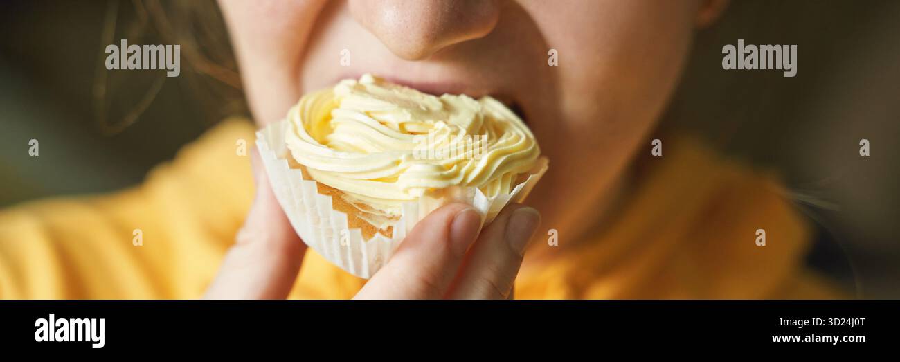 Young caucasian female enjoying delicious cupcake with creamy frosting close-up Stock Photo