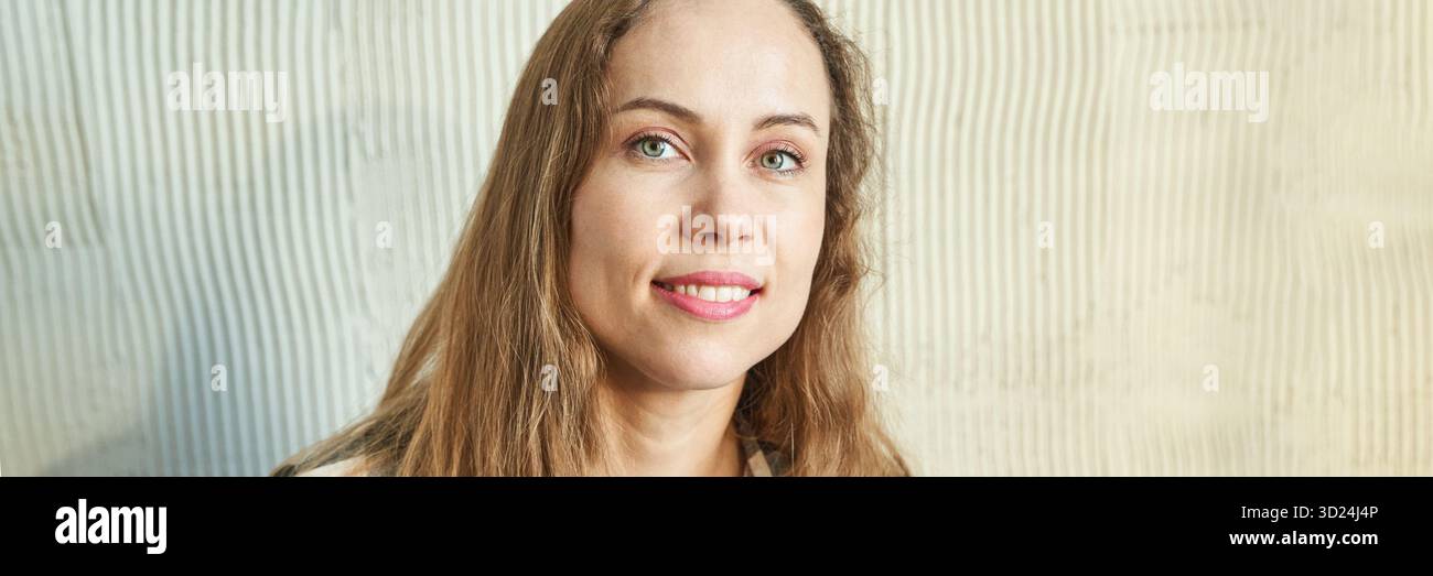 Smiling caucasian female adult with long brown hair against textured background Stock Photo