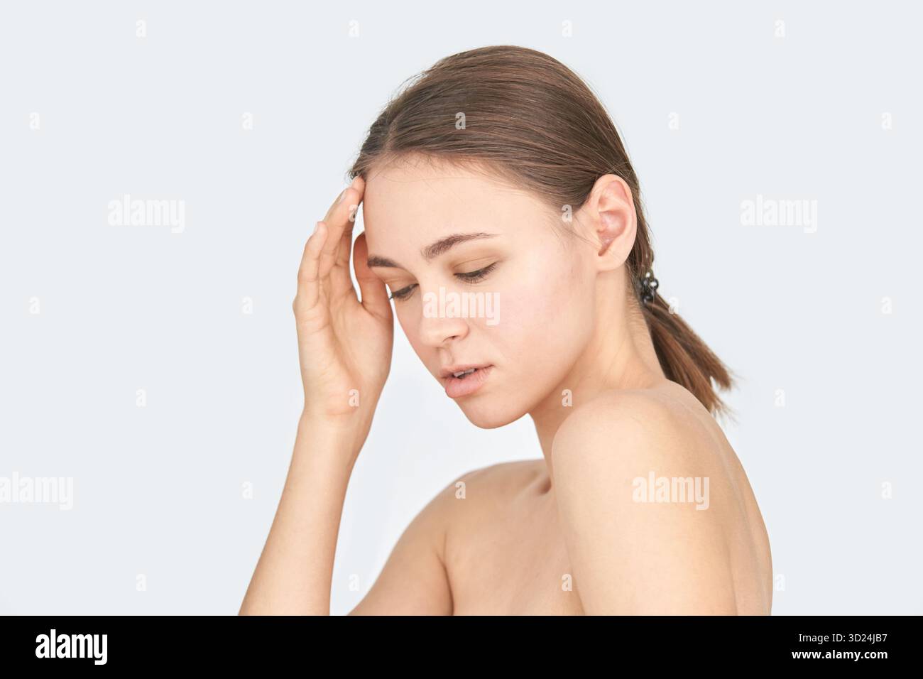 Young caucasian female with hand on head in thoughtful pose against neutral Stock Photo