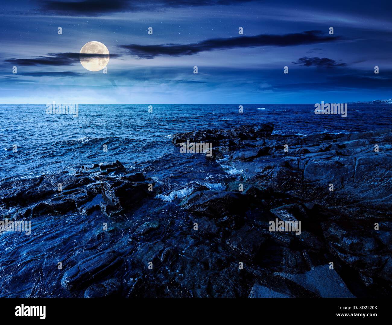night landscape of rocky sea coast. beautiful full moon over horizon. summer coastline scenic view. composite scene during midnight. magical seascape Stock Photo