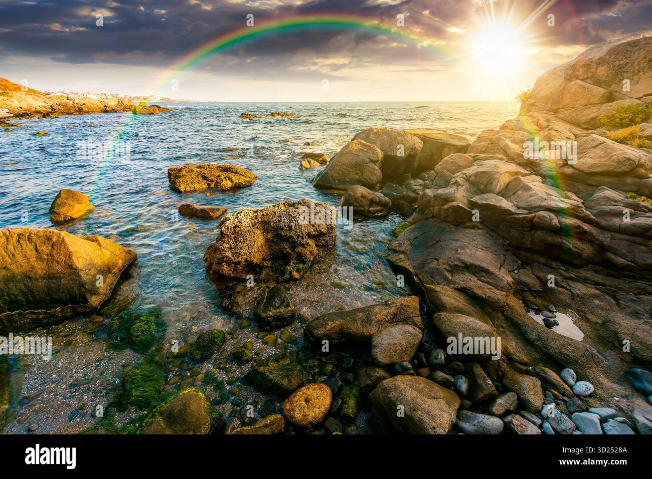sunset at the rocky sea beach. beautiful view of coast landscape in summer. sun over horizon and cloudy sky. dramatic scenery with rock formations und Stock Photo