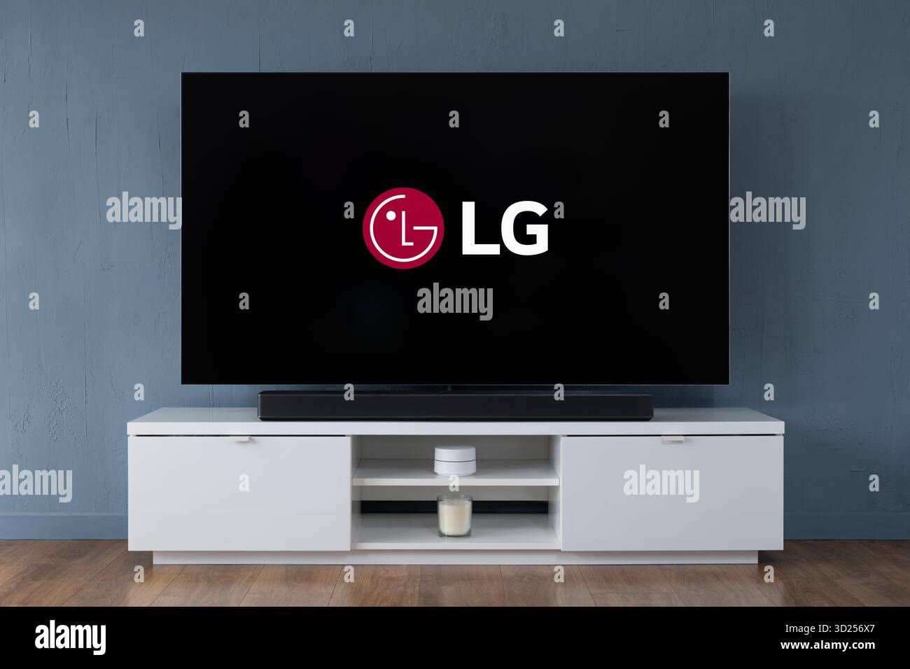 A 2025 LG OLED widescreen television is seen sat upon a white cabinet in a contemporary living room. Stock Photo