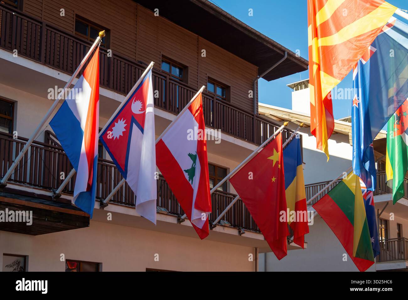 Multiple national flags flutter in the breeze, hanging from a balcony ...