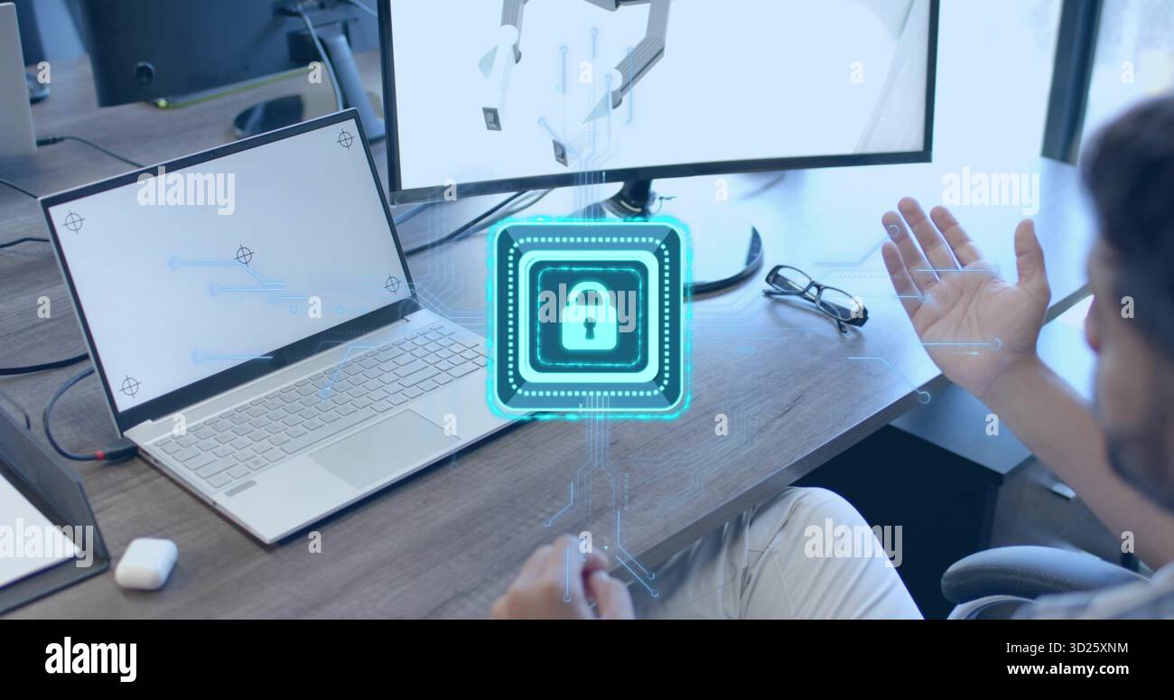 Gesturing man in shirt touching holographic lock icon above desk, with laptop, monitor, copy space Stock Photo