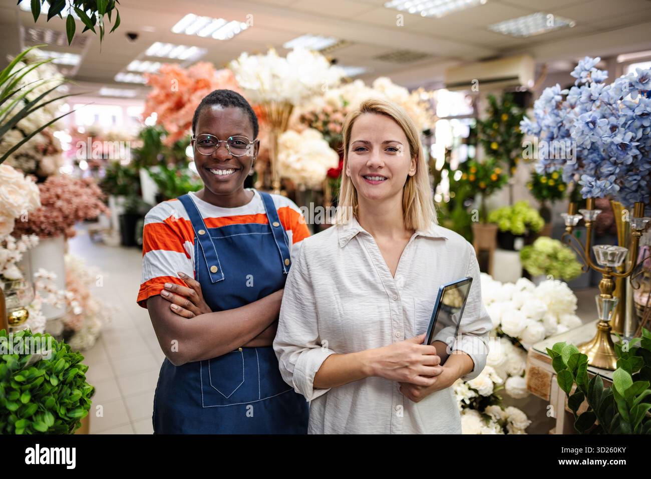 Two Smiling Florists Posing in Flower Shop with Digital Tablet Stock Photo