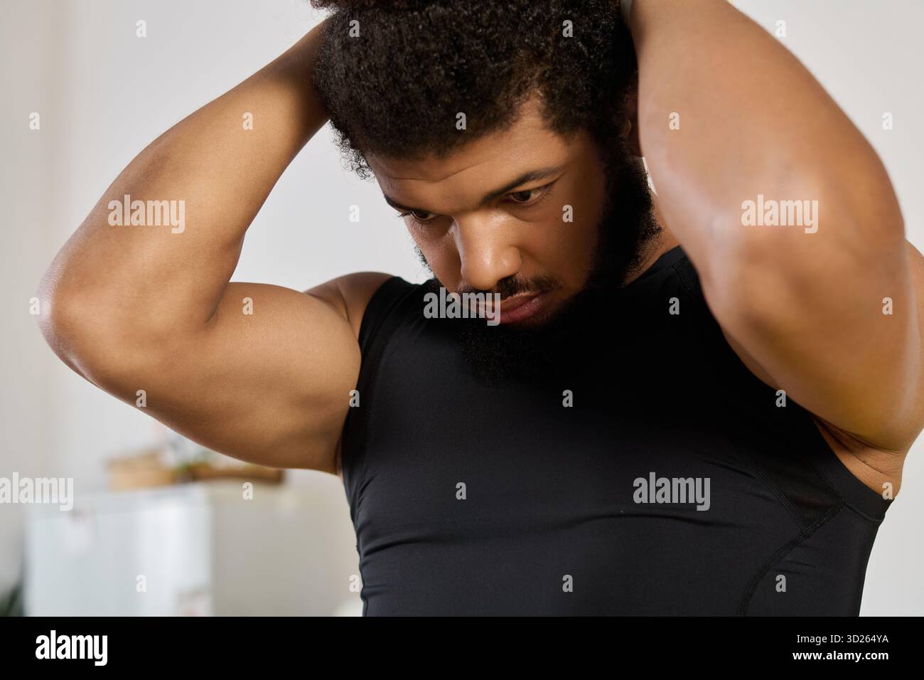 An athletic man adjusts his hair while getting ready to exercise at home. Stock Photo