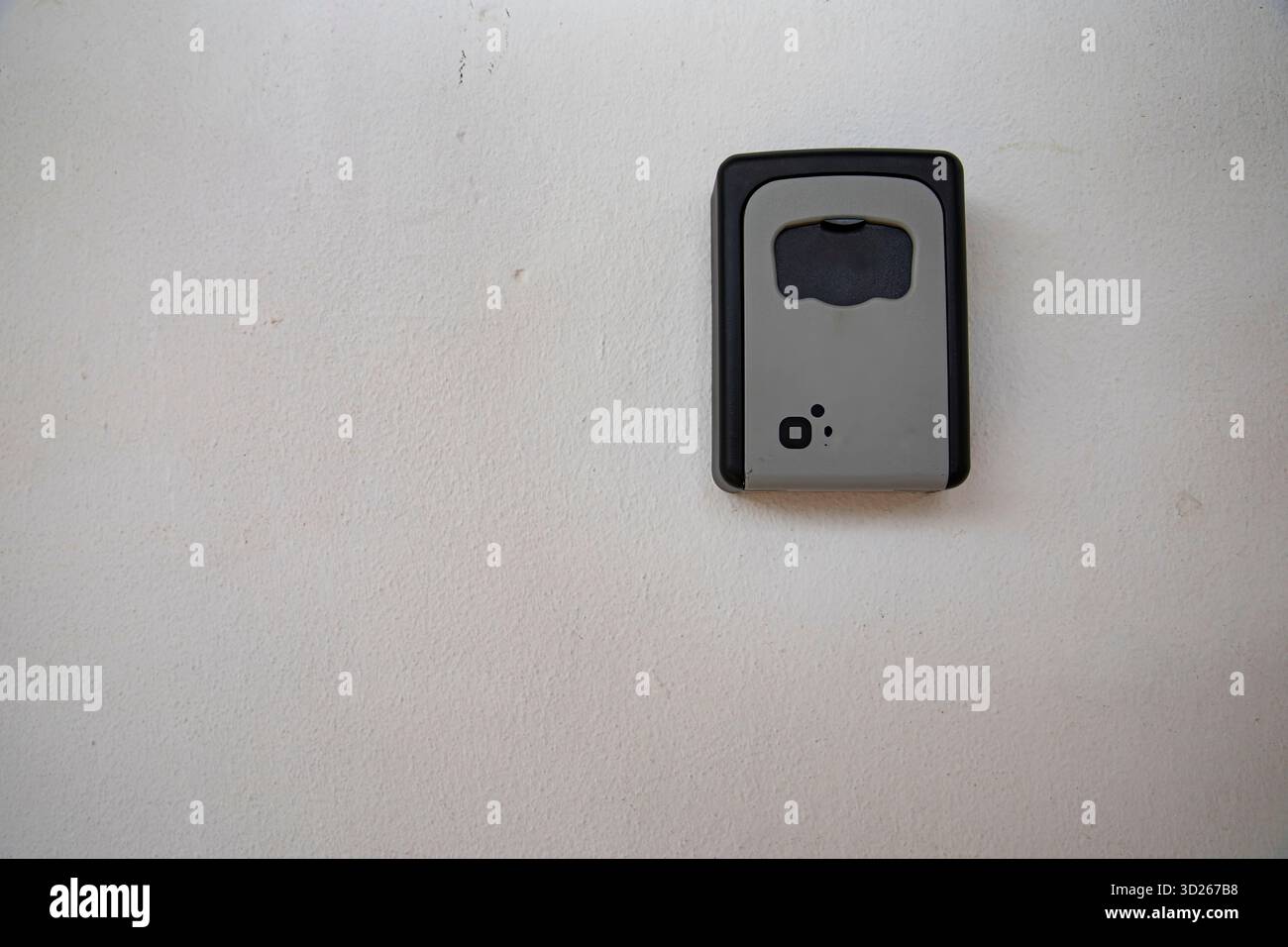 Metal key lock box mounted on textured white wall Stock Photo