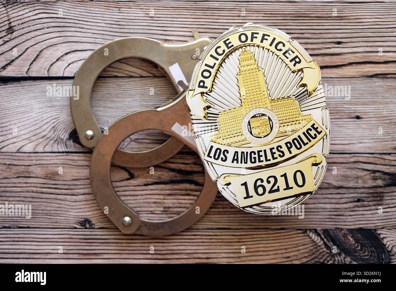 KYIV, UKRAINE - SEPTEMBER 17, 2025 US LAPD Police officer badge with handcuffs on wooden table close up Stock Photo