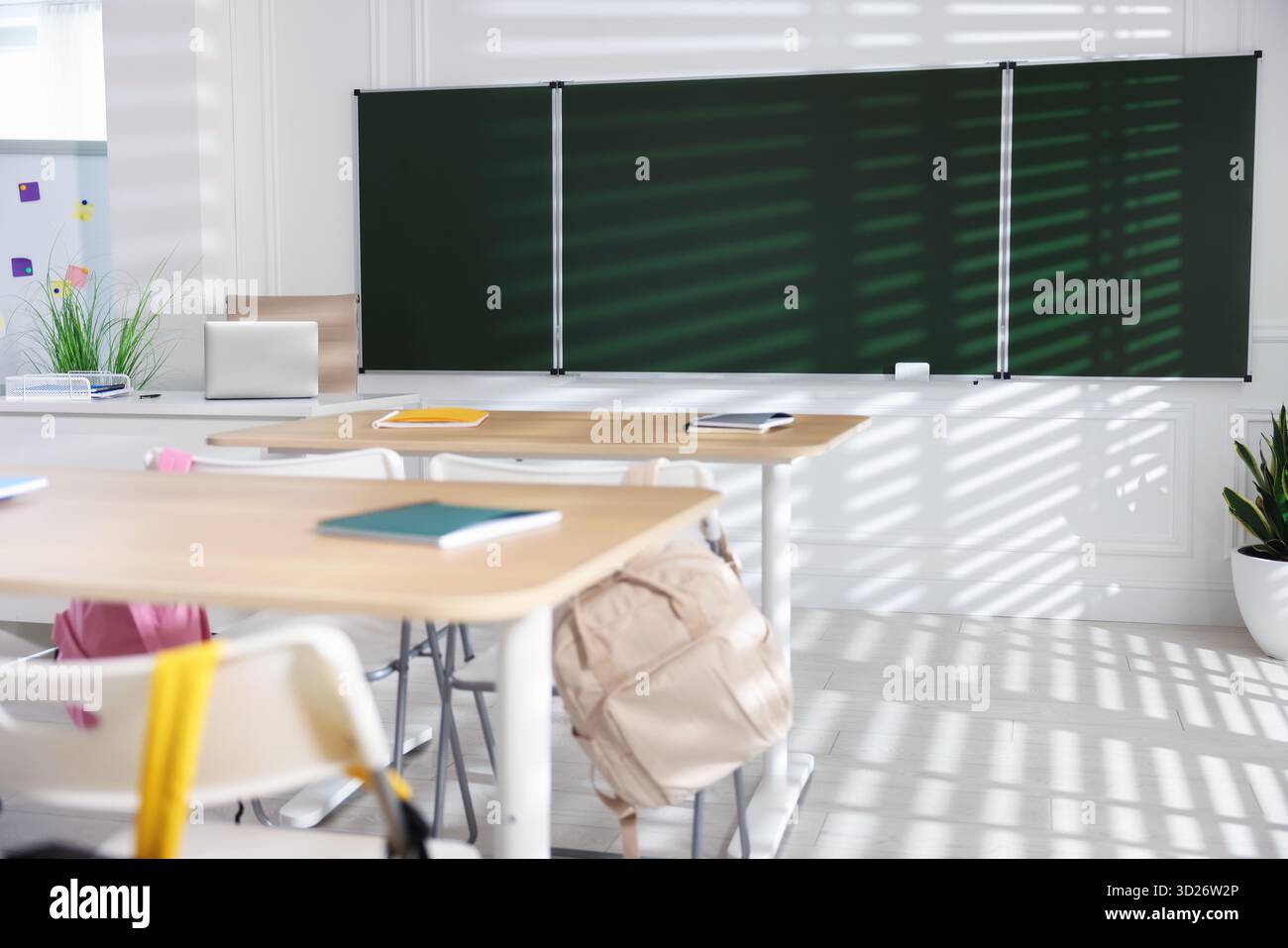 Green chalkboard, desks and chairs with backpacks in classroom Stock ...
