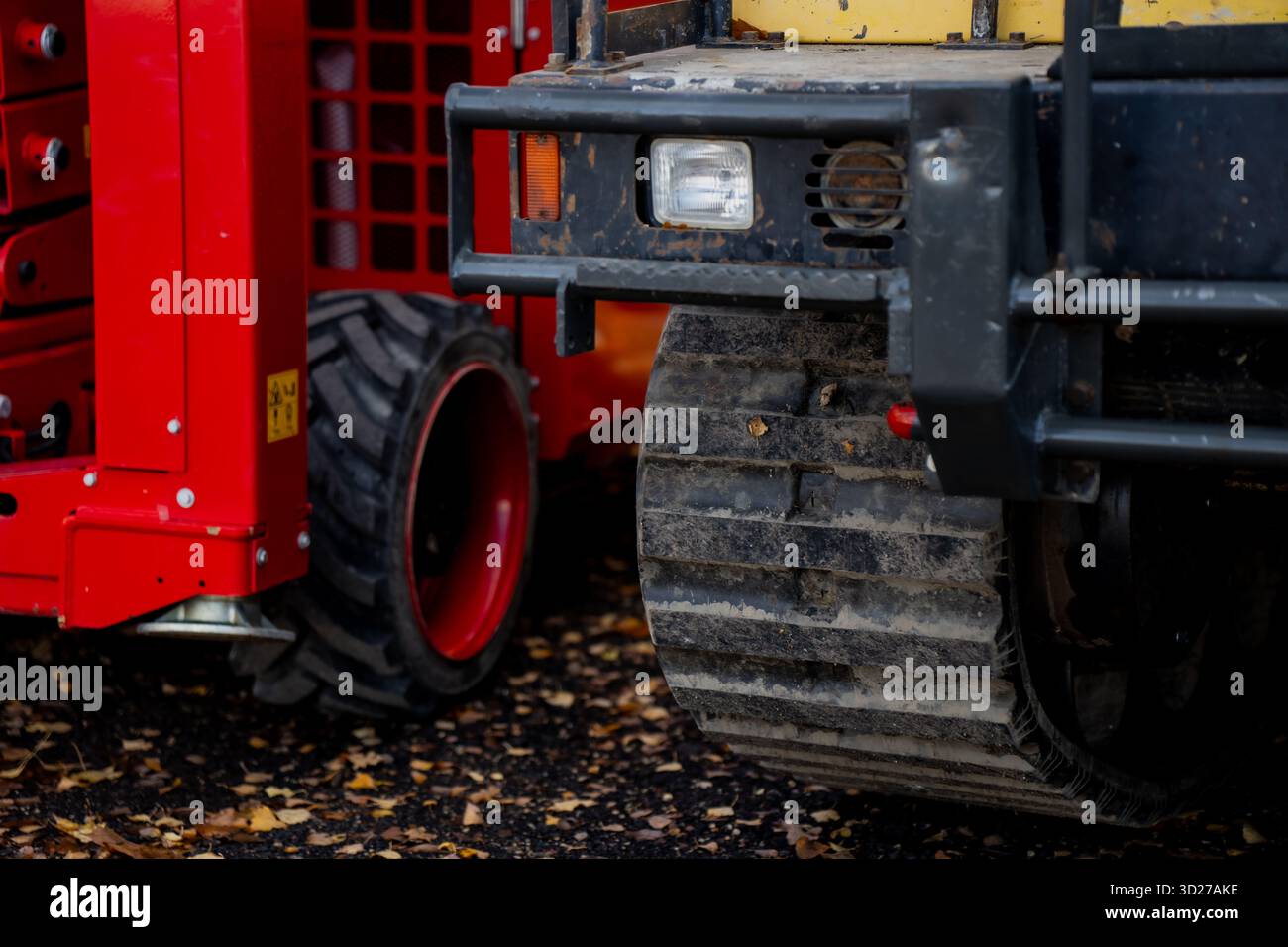 Compact track loader next to red mobile lift platform demonstrating ...
