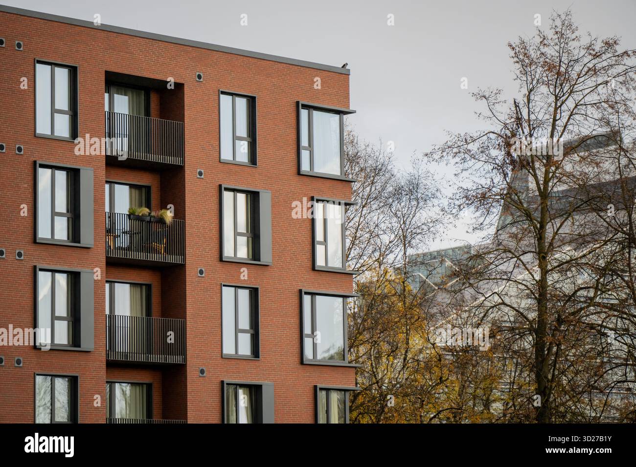 New apartment building with red brick facade and trees in front ...