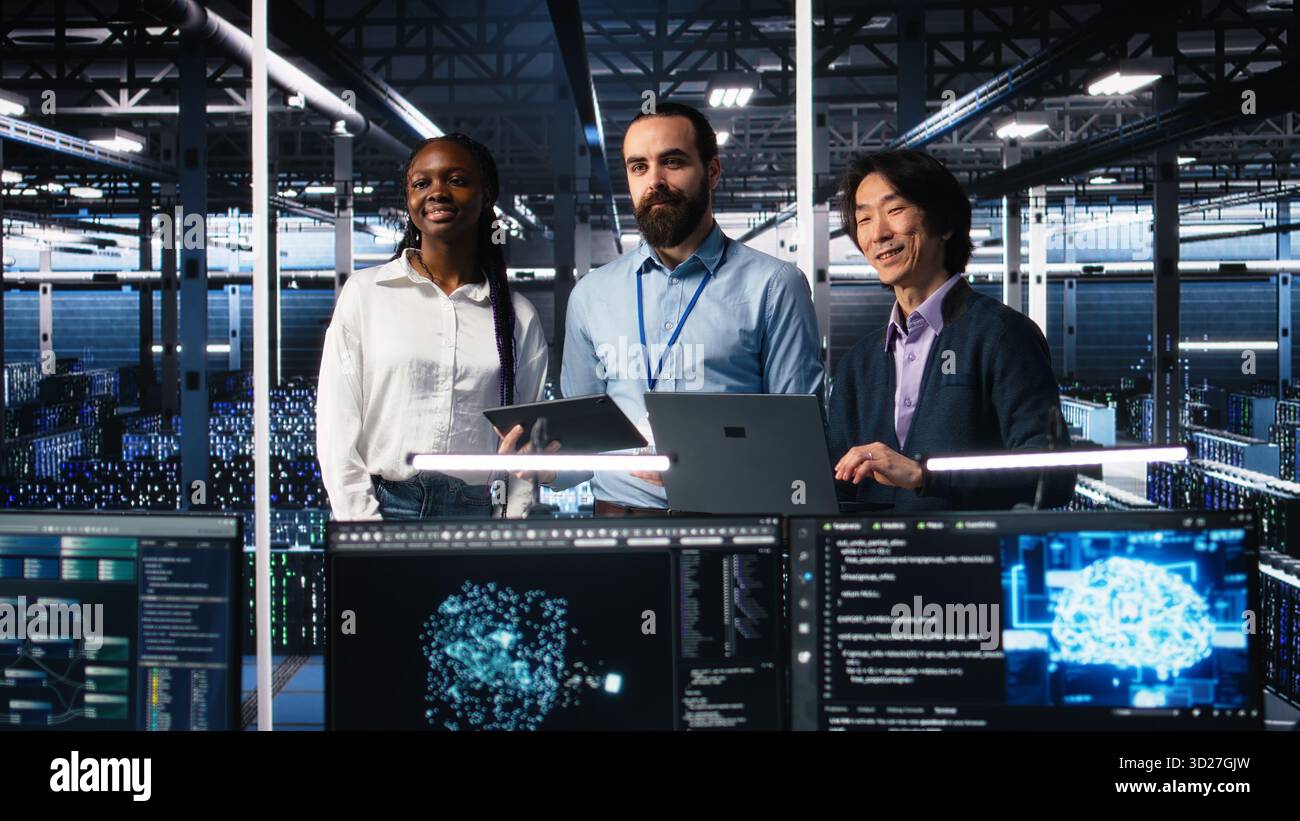 Happy data center colleagues collaborating on neural network software development. Cheerful teamworking server hub coworkers implementing machine learning technology in workplace, camera A Stock Photo