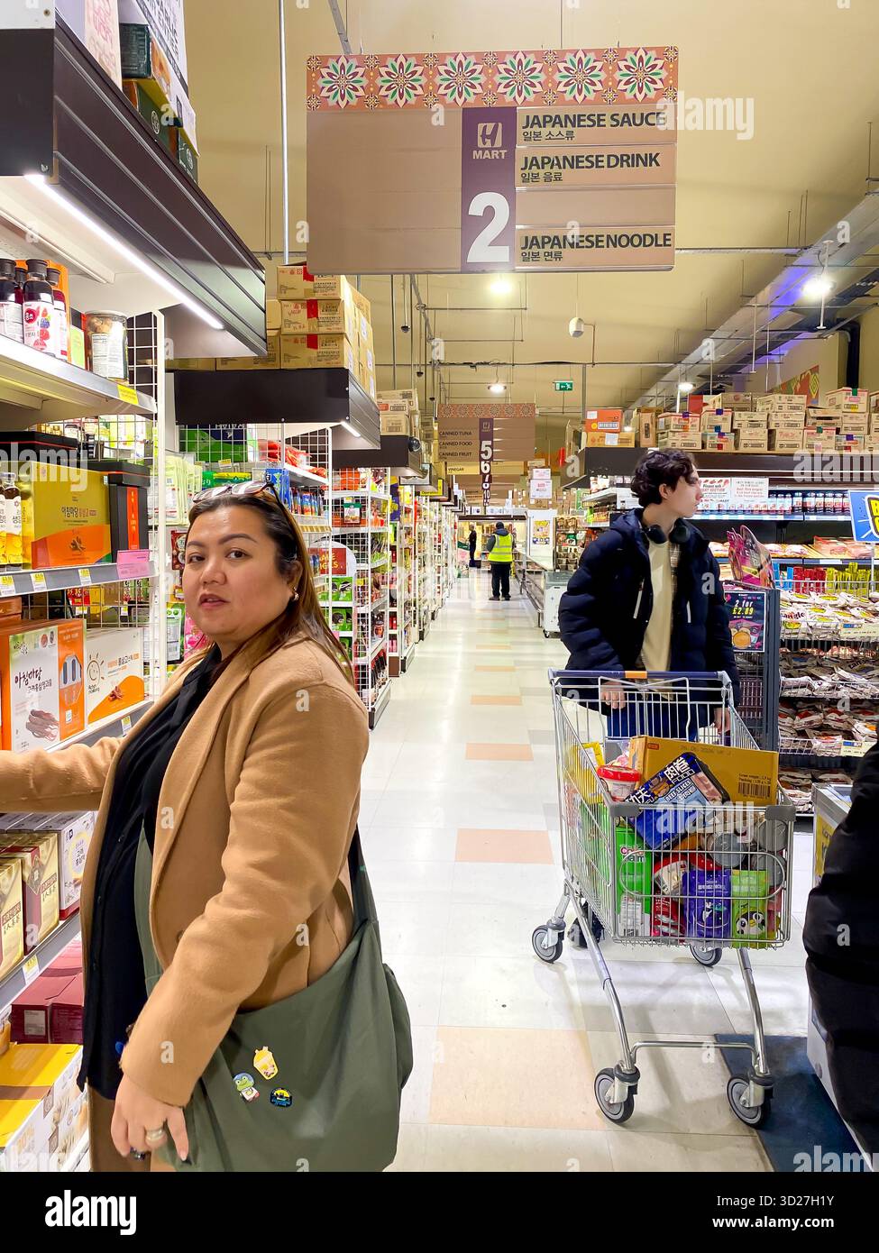 A woman chooses products in an Asian supermarket in London, UK - Smartphone Captured Stock Image
