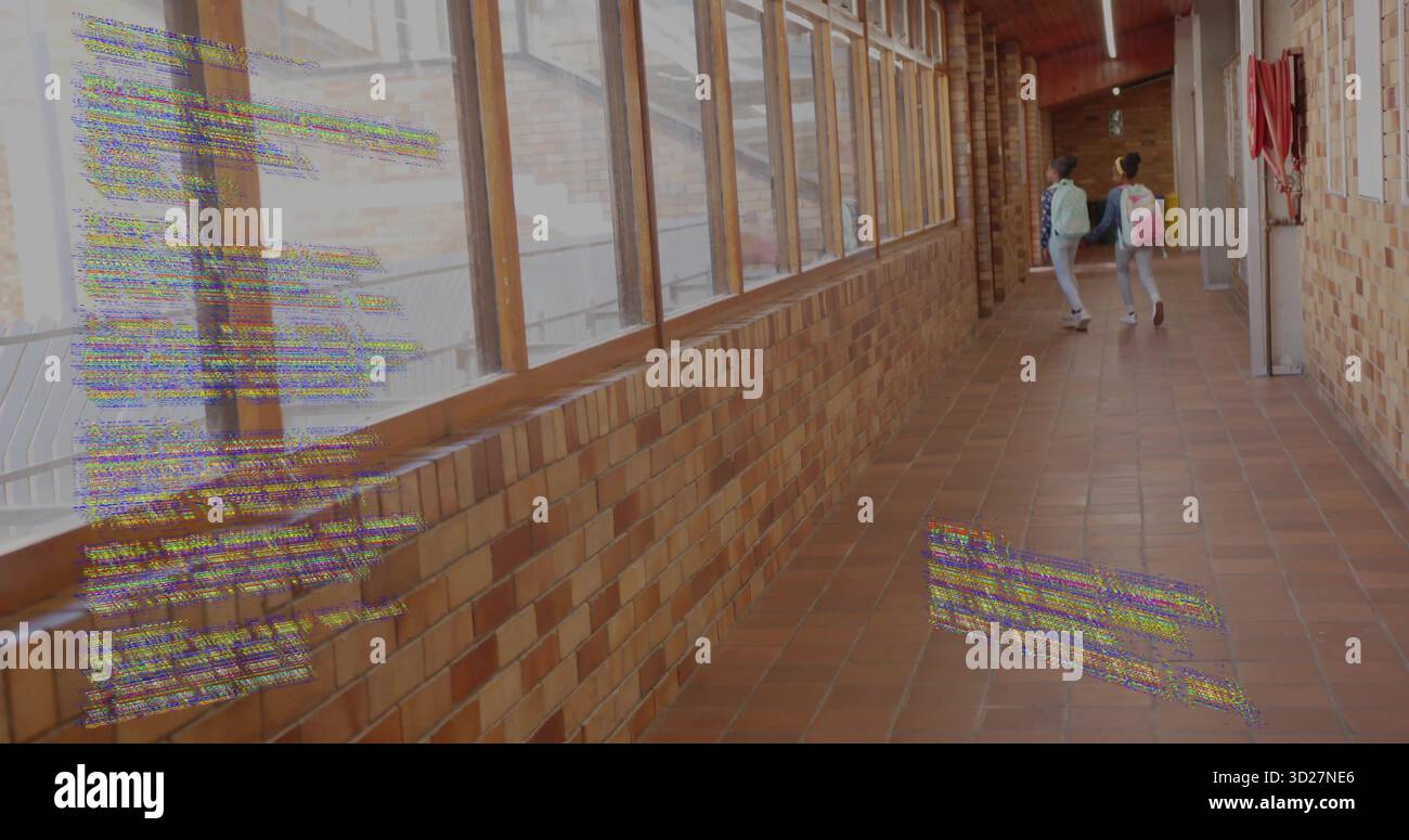 Walking two schoolgirls carrying backpacks in school corridor, with fire extinguisher, copy space Stock Photo